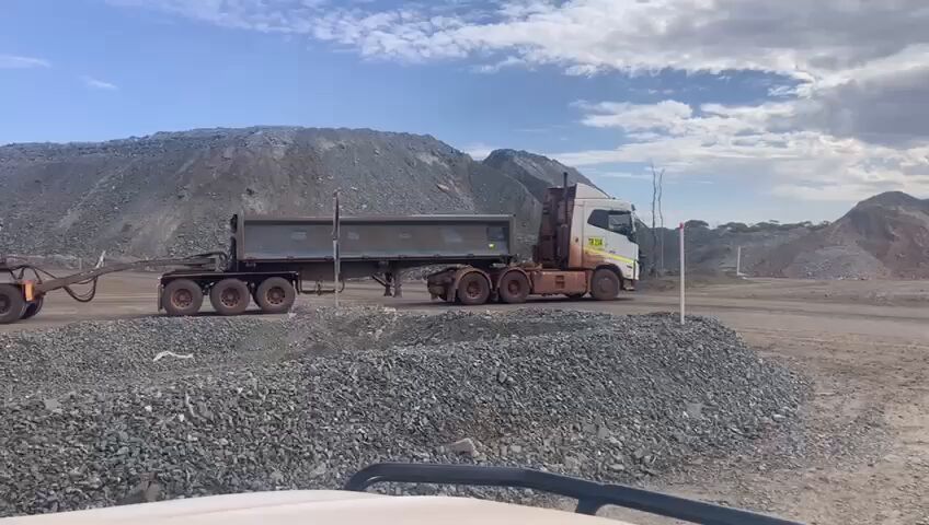 Road trains beside an ore stockpile